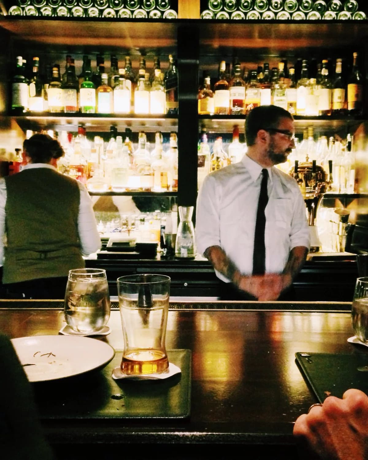 A bartender pouring a cocktail at a dimly lit bar