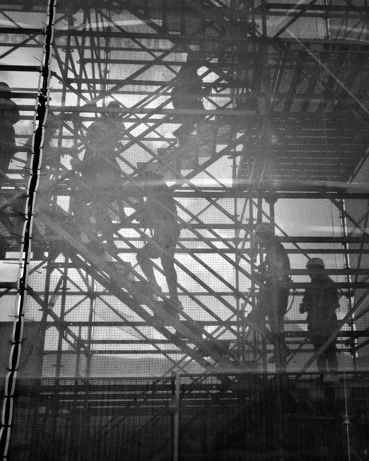 Construction workers on scaffolding, silhouetted against a building