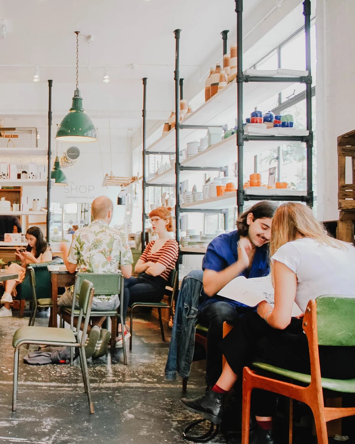 A bright, busy barbershop and salon floor with clients in chairs