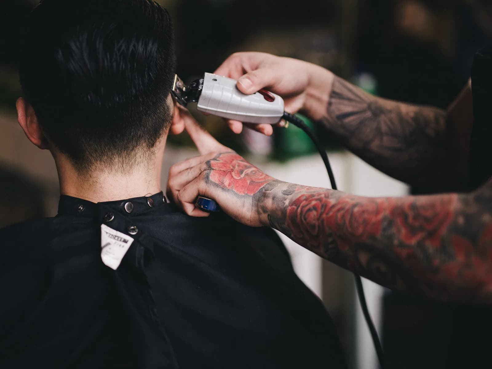 A barber finishing a haircut in a busy barbershop