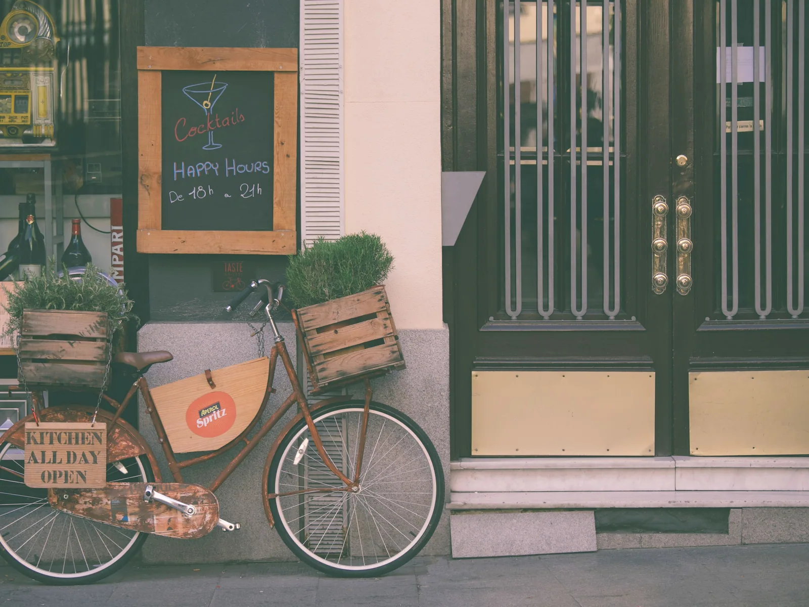 A bar façade with a bicycle parked out front and a chalkboard happy-hour sign